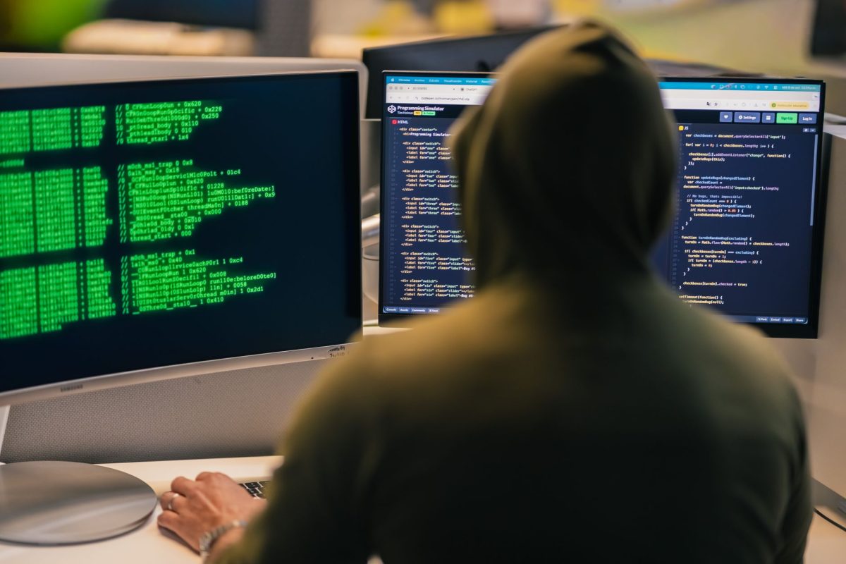 person looking at dual monitors with complex code and neural network diagram